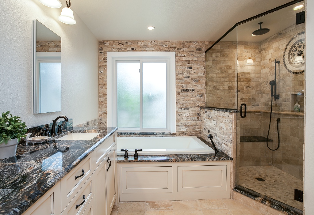 Bathroom surrounded with polished granite along with bathtub and shower.